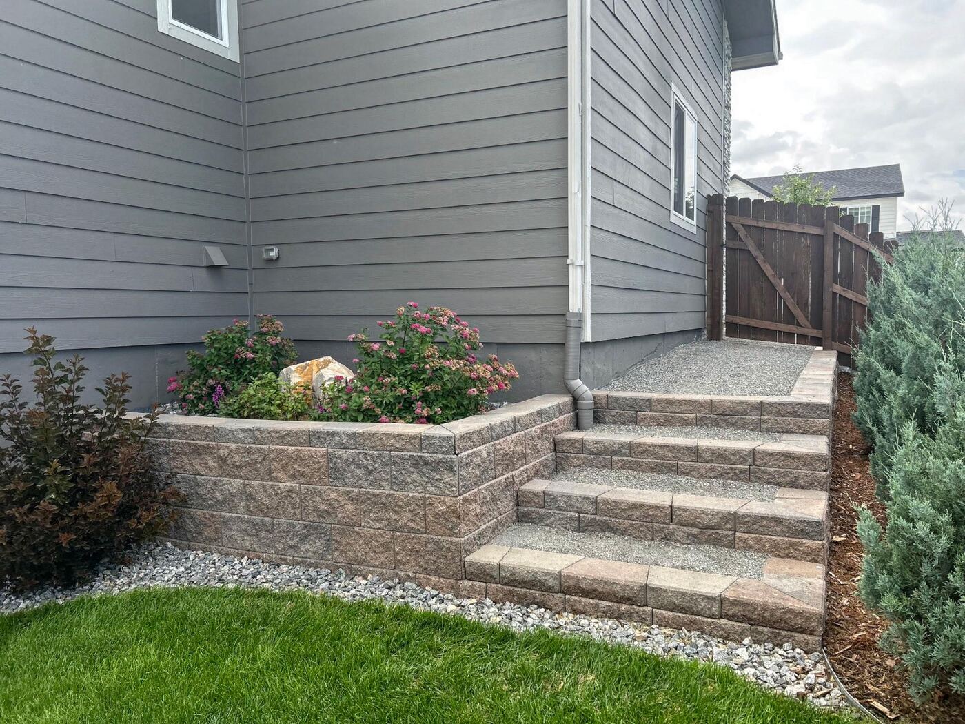 Stone retaining wall with steps and seasonal flowers.